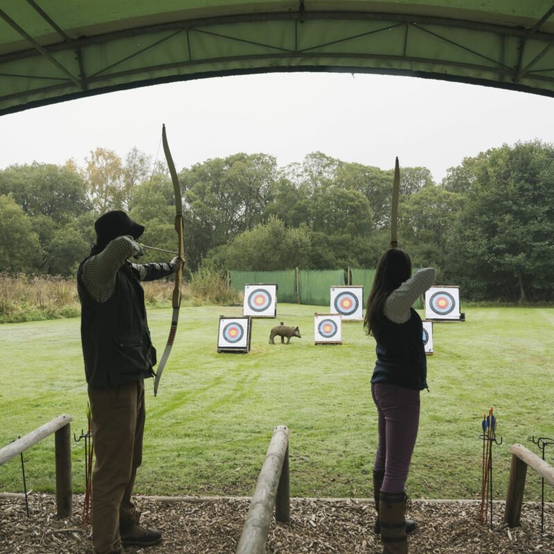 two people drawing their bows for archery