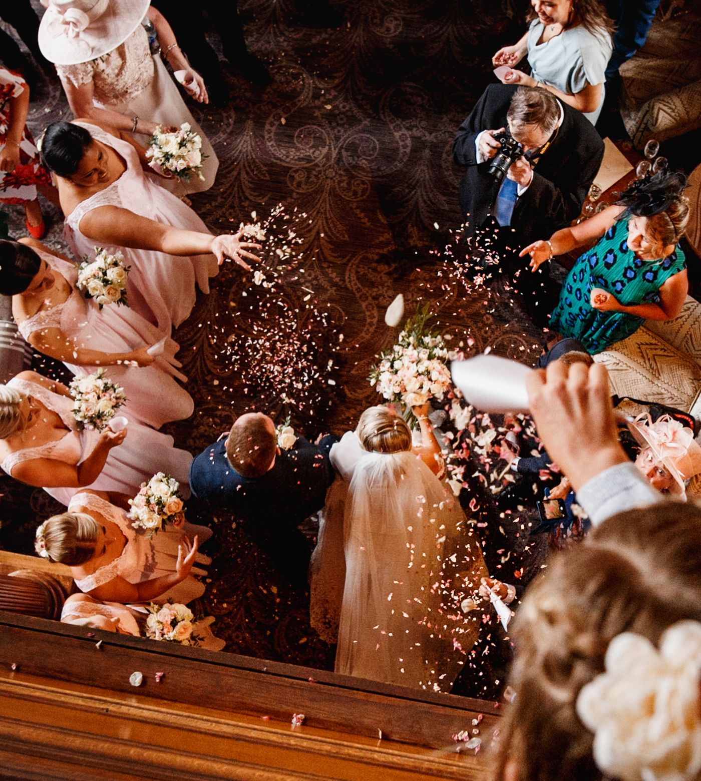 Birds eye view of guests throwing confetti on married couple  