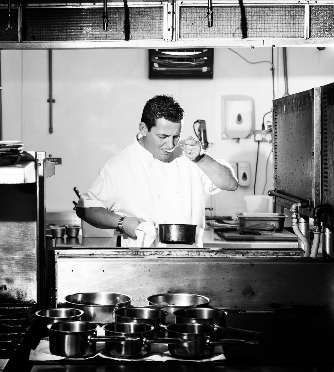 Chef in kitchen tasting food 