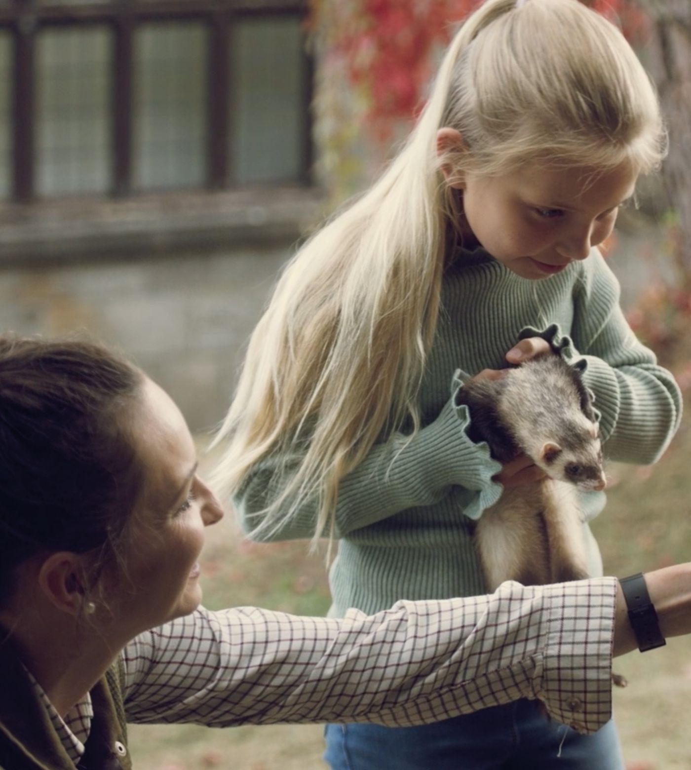 Girl holding ferret with trainer 