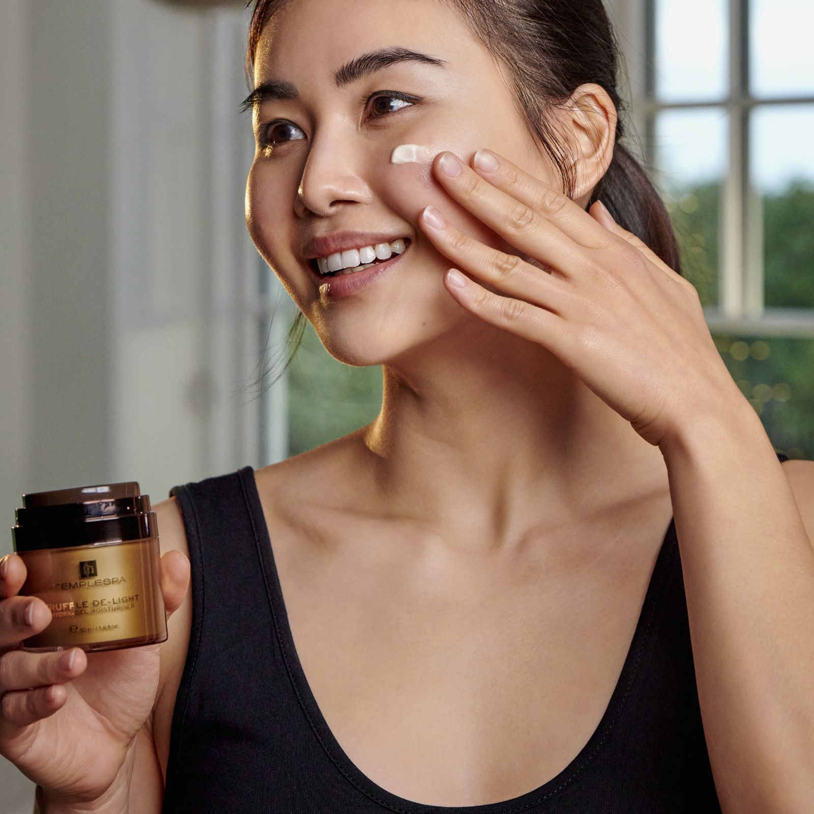 Woman applying cream to her face and smiling 