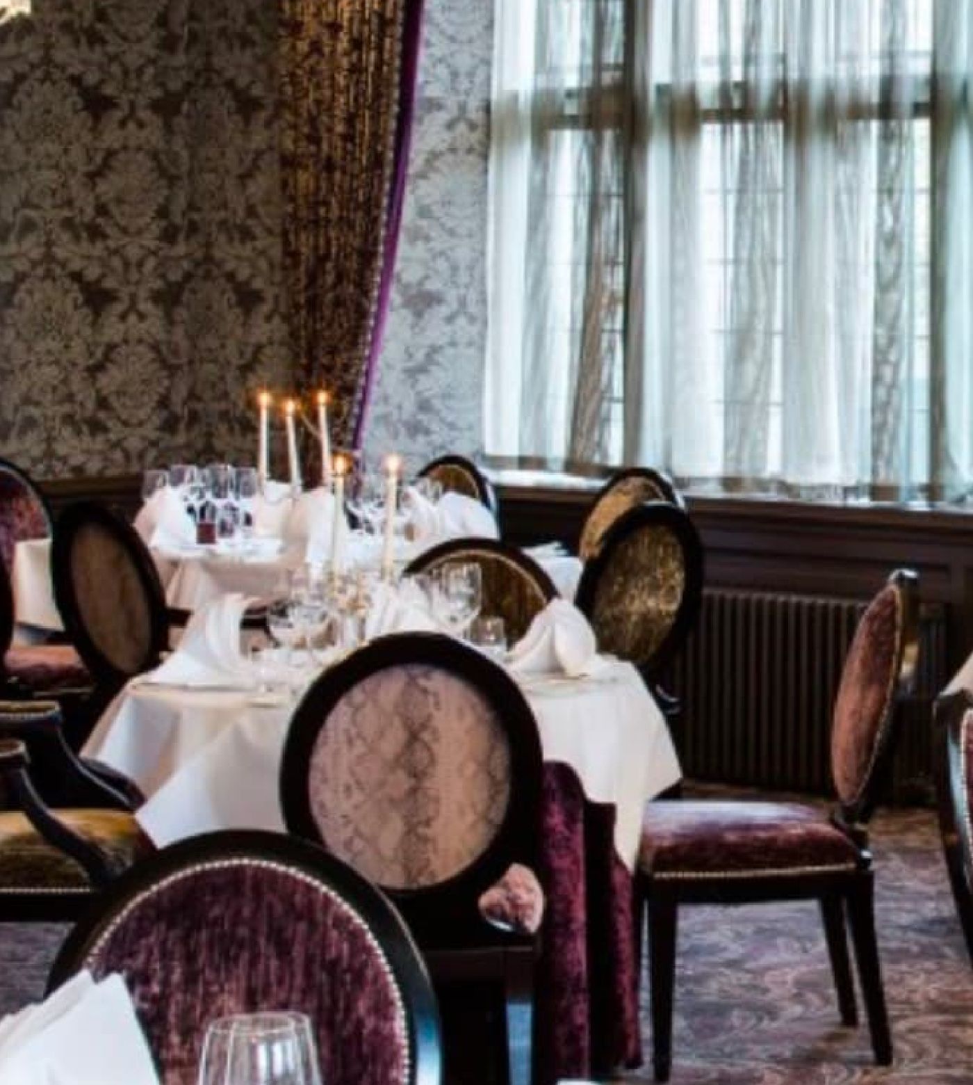 multiple tables and chairs with candles in room 